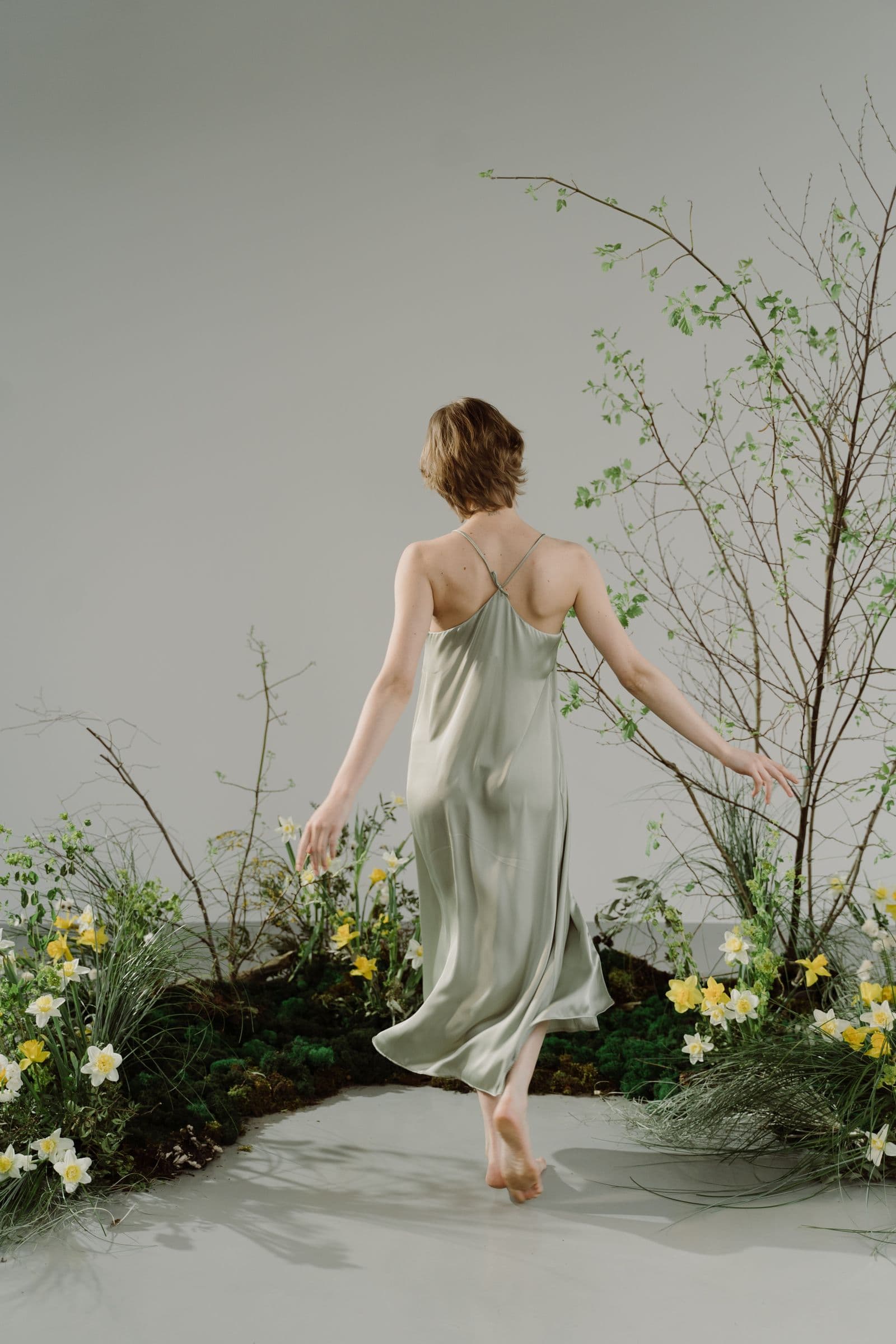 A model in a flowing slip dress among spring blossom